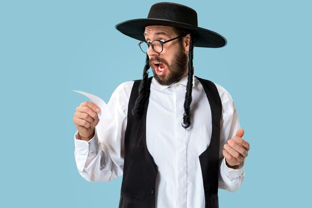 Retrato de un joven judío ortodoxo con boleta de apuestas en el estudio. Vacaciones, celebración, judaísmo, concepto de apuestas.