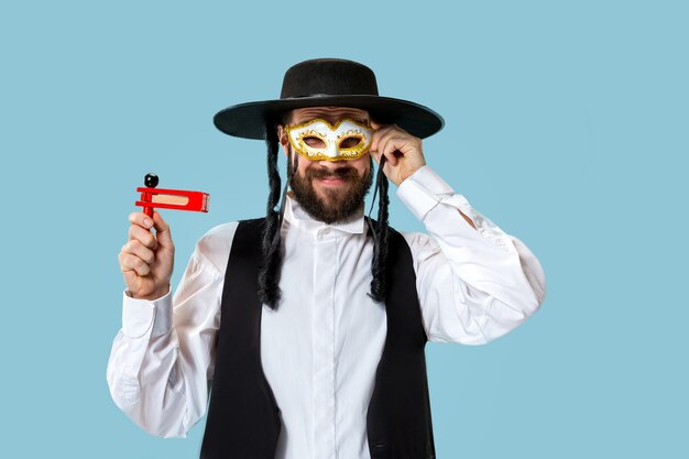 Retrato de un joven judío ortodoxo con trinquete grager de madera durante el festival Purim. Vacaciones, celebración, judaísmo, concepto de religión.