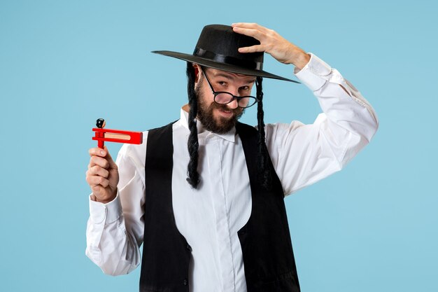 Retrato de un joven judío ortodoxo con trinquete grager de madera durante el festival Purim. Vacaciones, celebración, judaísmo, tradición, concepto de religión.