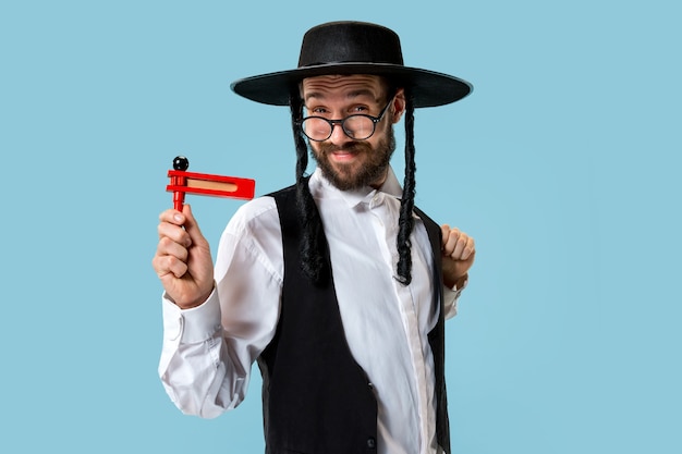 Retrato de un joven judío ortodoxo con trinquete grager de madera durante el festival Purim. Vacaciones, celebración, judaísmo, tradición, concepto de religión.