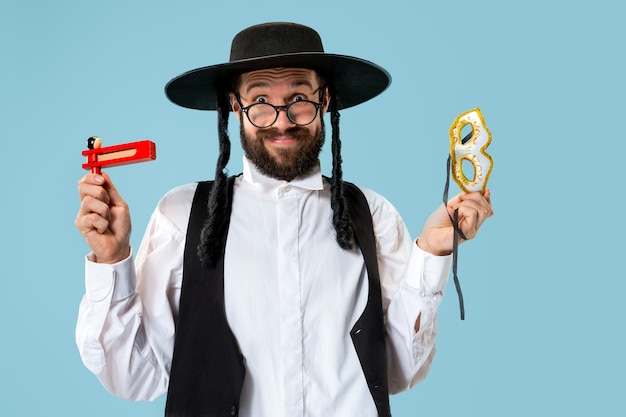 Retrato de un joven judío ortodoxo con trinquete grager de madera durante el festival Purim