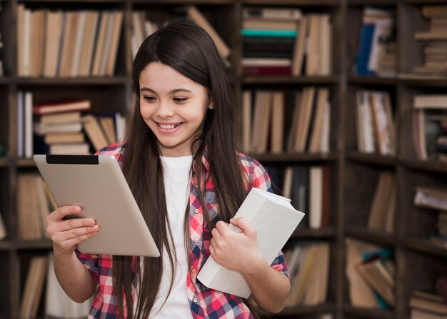 Retrato de joven jugando en tableta en la biblioteca