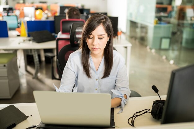 Retrato de una joven latina en casual trabajando en una laptop