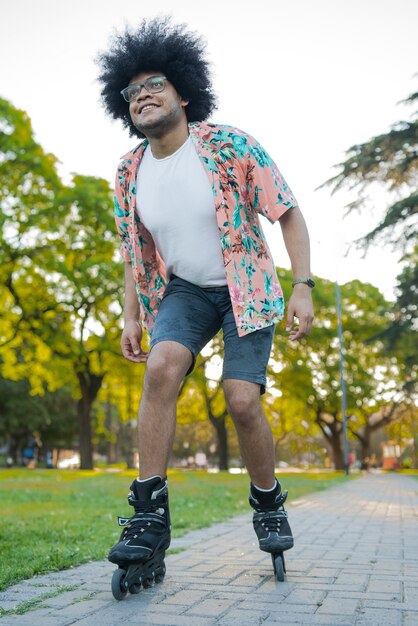Retrato de joven latino disfrutando mientras patina al aire libre en la calle