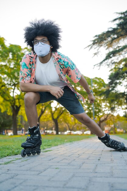 Foto gratuita retrato de joven latino con mascarilla mientras patina al aire libre en la calle