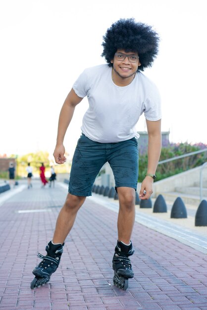 Retrato de joven latino patinaje al aire libre en la calle