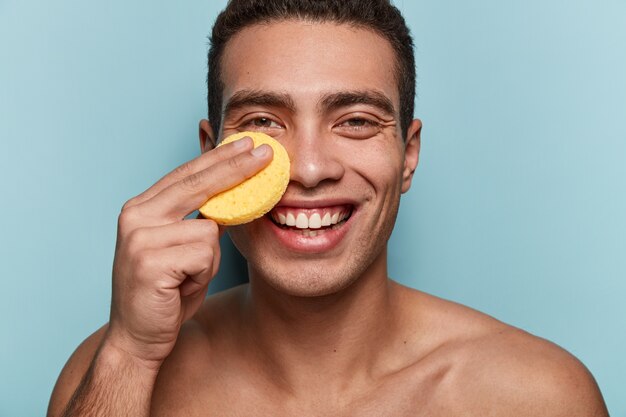 Retrato de joven limpiando la cara con una esponja