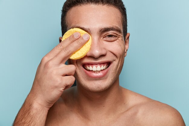 Retrato de joven limpiando la cara con una esponja