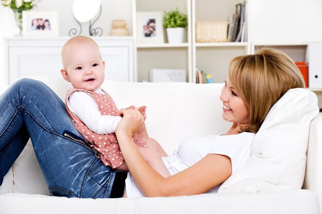 Retrato de joven madre feliz con bebé recién nacido en casa