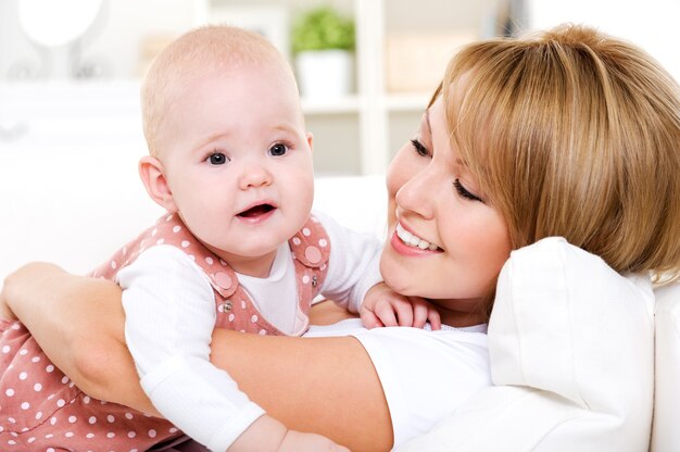 Retrato de joven madre feliz con bebé recién nacido en casa