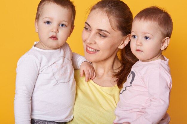 Retrato de joven madre con sus gemelos pequeños