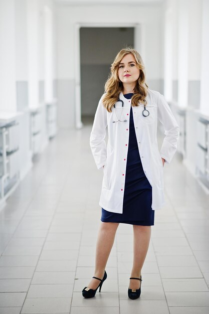 Retrato de un joven médico atractivo con bata blanca con estetoscopio posando en el hospital