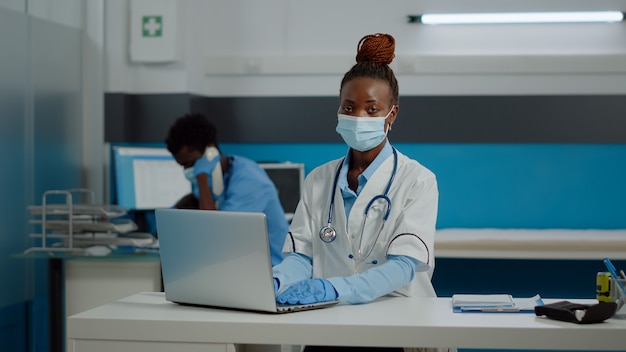 Retrato de joven médico con tecnología portátil en el escritorio