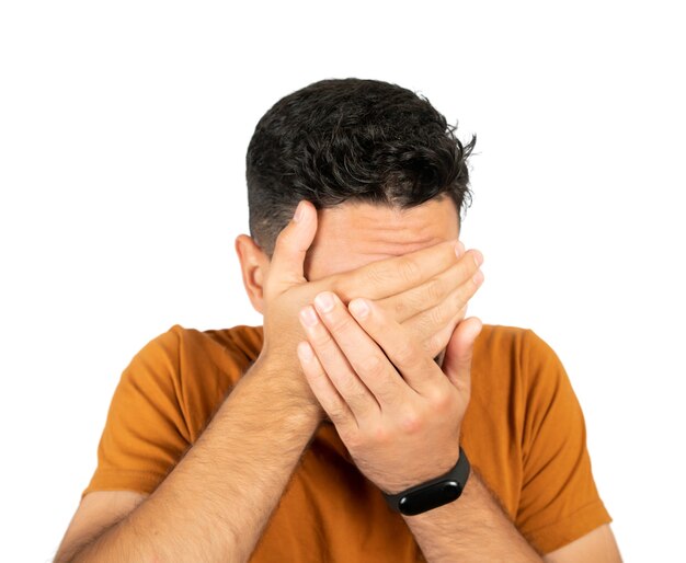 Retrato de joven mirando asustado y cubriendo su rostro contra un fondo blanco en el estudio.