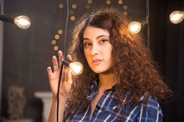 Retrato de una joven modelo en camisa a cuadros posando junto a las lámparas