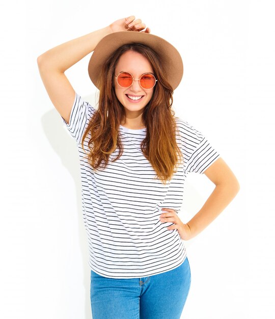 Retrato de joven modelo elegante mujer riendo en ropa casual de verano en sombrero marrón con maquillaje natural aislado en la pared blanca. Parpadeo