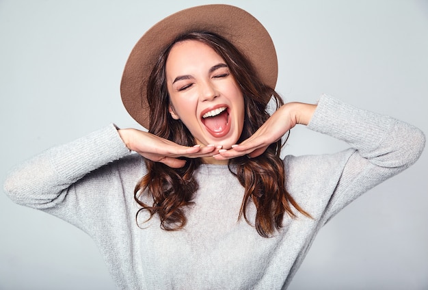 Retrato de joven modelo elegante riendo en ropa casual gris de verano en sombrero marrón con maquillaje natural