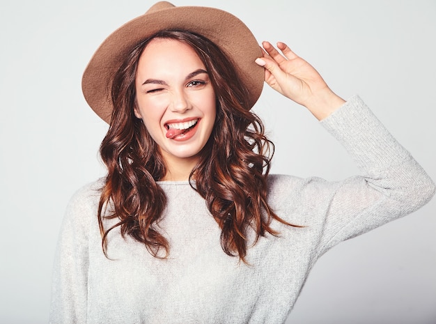 Retrato de joven modelo elegante riendo en ropa casual gris de verano en sombrero marrón con maquillaje natural