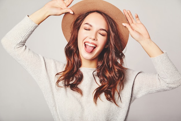 Retrato de joven modelo elegante riendo en ropa casual gris de verano en sombrero marrón con maquillaje natural