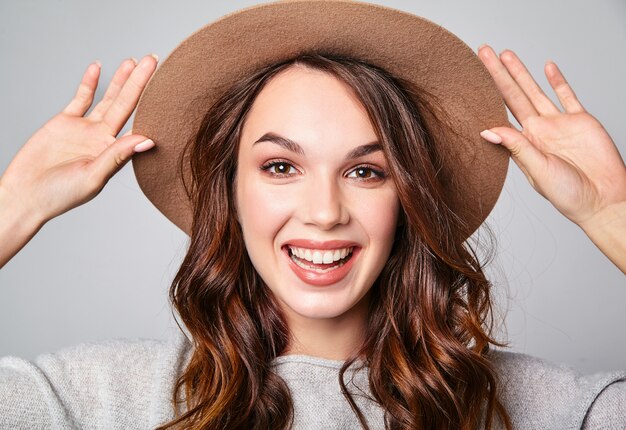 Retrato de joven modelo elegante riendo en ropa casual gris de verano en sombrero marrón con maquillaje natural