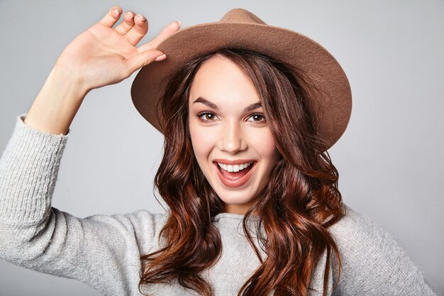 Retrato de joven modelo elegante riendo en ropa casual gris de verano en sombrero marrón con maquillaje natural