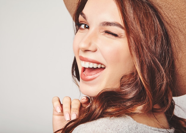 Retrato de joven modelo elegante riendo en ropa casual gris de verano en sombrero marrón con maquillaje natural