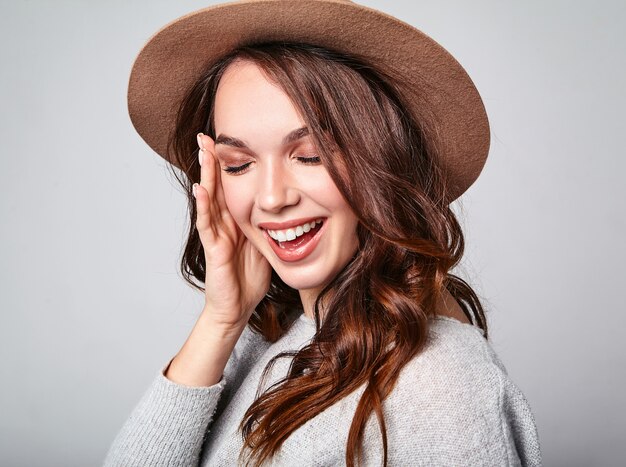 Retrato de joven modelo elegante riendo en ropa casual gris de verano en sombrero marrón con maquillaje natural