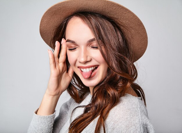 Retrato de joven modelo elegante riendo en ropa casual gris de verano en sombrero marrón con maquillaje natural