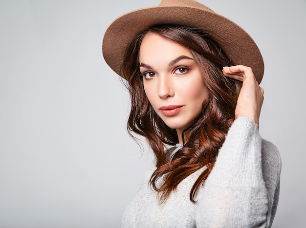Retrato de joven modelo elegante riendo en ropa casual gris de verano en sombrero marrón con maquillaje natural