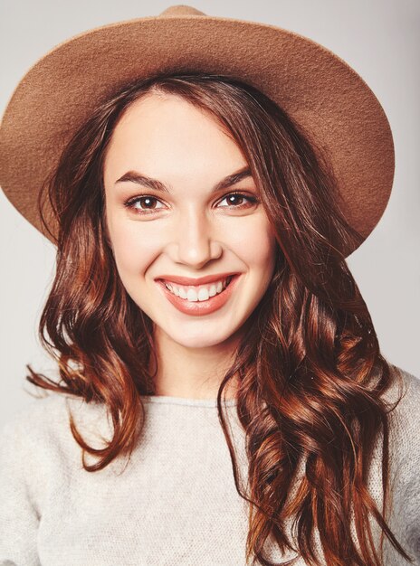 Retrato de joven modelo elegante riendo en ropa casual gris de verano en sombrero marrón con maquillaje natural