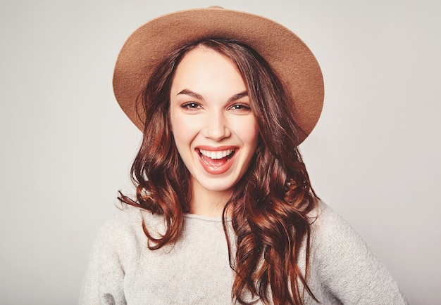 Retrato de joven modelo elegante riendo en ropa casual gris de verano en sombrero marrón con maquillaje natural