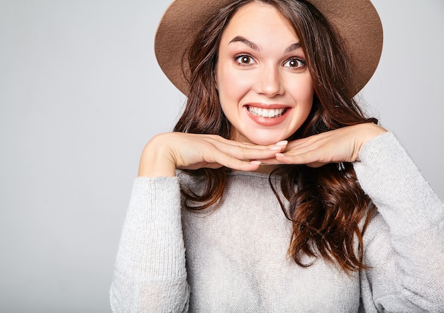 Retrato de joven modelo elegante riendo en ropa casual gris de verano en sombrero marrón con maquillaje natural