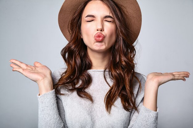 Retrato de joven modelo elegante riendo en ropa casual gris de verano en sombrero marrón