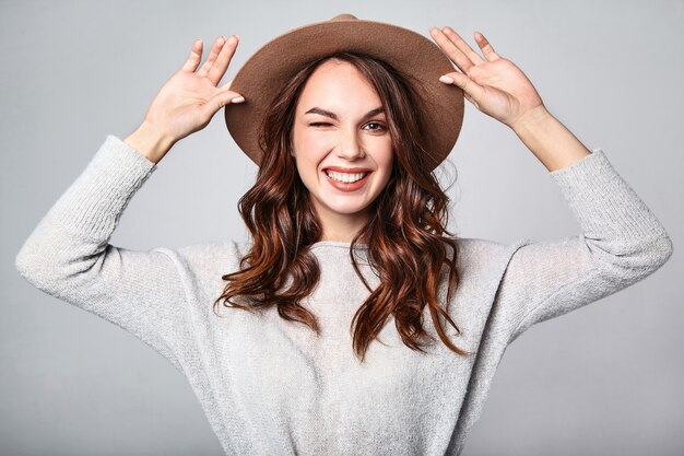 Retrato de joven modelo elegante riendo en ropa casual gris de verano en sombrero marrón