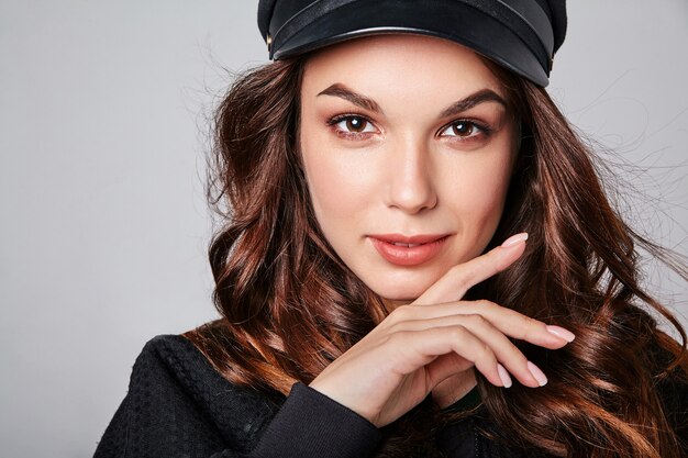 Retrato de joven modelo elegante riendo en ropa casual de verano negro en gorra con maquillaje natural en gris