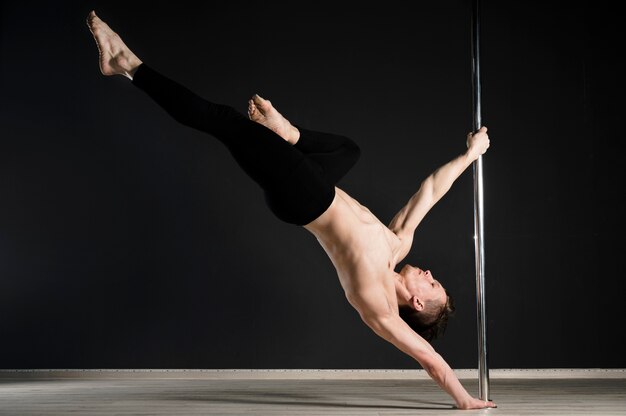 Retrato de joven modelo masculino realizando un pole dance