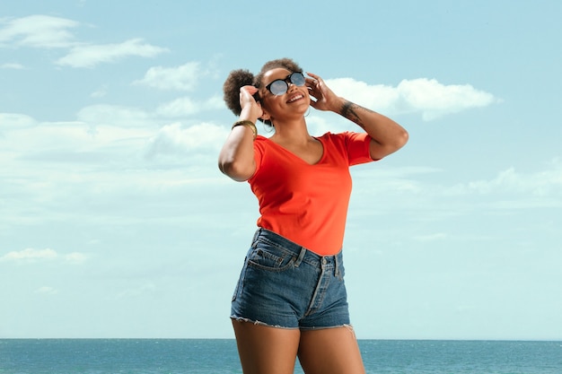 Foto gratuita retrato de joven modelo de moda femenina sobre fondo de cielo azul.