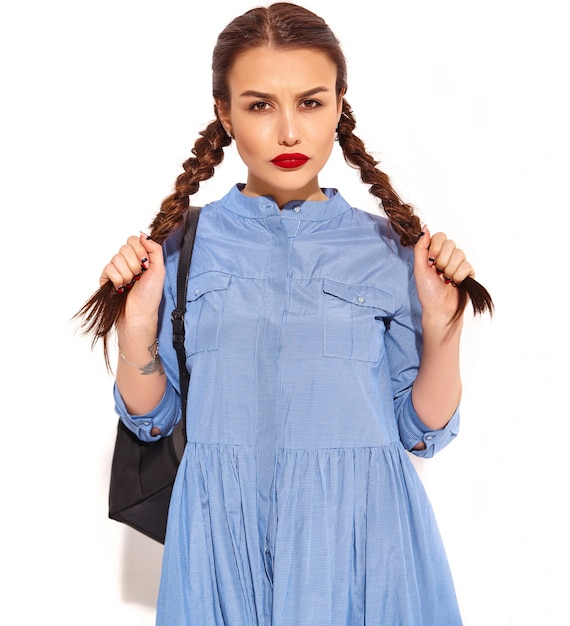 Retrato de joven modelo de mujer sonriente feliz con maquillaje brillante y labios rojos con dos coletas en manos en verano colorido vestido azul y mochila aislado