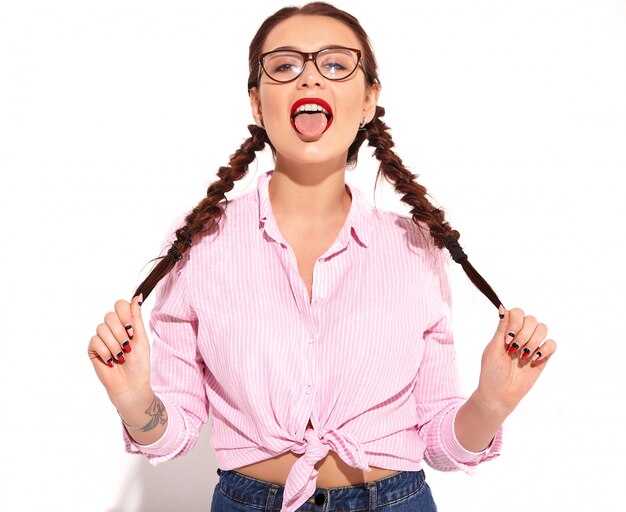 Retrato de joven modelo de mujer sonriente feliz con maquillaje brillante y labios rojos con dos coletas en verano colorida camisa atada de color rosa aislada