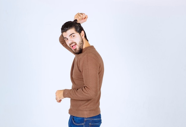 Retrato de un joven modelo sonriente mostrando su peinado contra la pared blanca. Foto de alta calidad