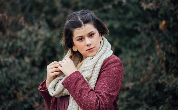 Retrato de una joven morena con una bufanda y un abrigo en el bosque en el otoño