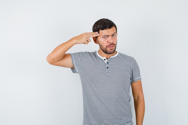 Retrato de joven mostrando gesto de suicidio en camiseta y mirando seria vista frontal