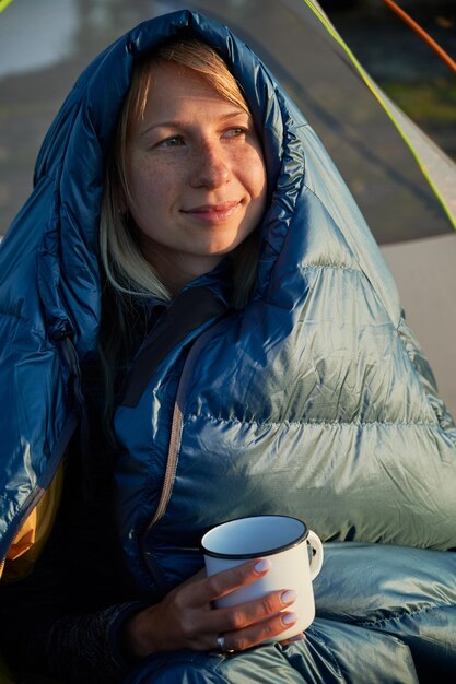 Retrato de joven mujer agradable en saco de dormir al aire libre