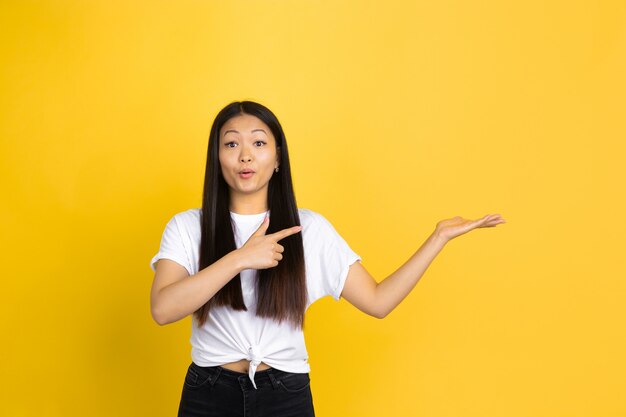 Retrato de joven mujer asiática aislada en la pared amarilla