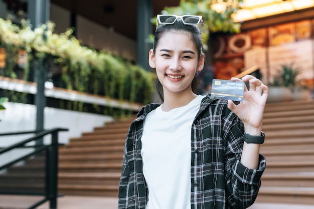 Retrato de joven mujer asiática con anteojos de pie en las escaleras con bolsa de papel de compras