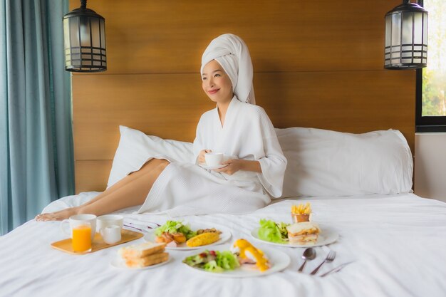 Retrato joven mujer asiática en la cama con desayuno en el dormitorio