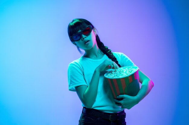 Retrato de joven mujer asiática en estudio degradado azul-púrpura en luz de neón