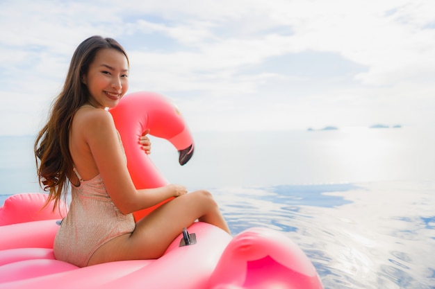 Retrato joven mujer asiática en flotador inflable flamingo alrededor de la piscina al aire libre en el hotel resort
