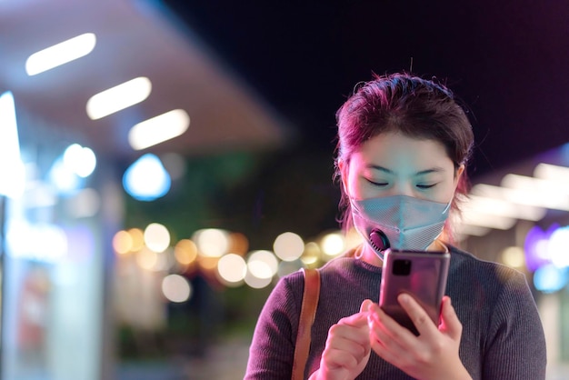 Retrato de una joven mujer asiática con una máscara protectora facial para evitar la propagación del virus, uso manual, tecnología de teléfonos inteligentes, comunicación, nuevo concepto de estilo de vida normal