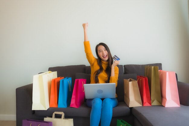 Retrato joven mujer asiática con ordenador portátil con teléfono móvil inteligente y tarjeta de crédito para compras en línea